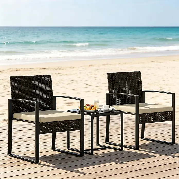 SONNENH Balkonmöbel-Set - 3 -tlg., Schaumstoff, Glas, Polyester, Rattan, Stahl, Schwarz/Braun/Khaki - Braunes Rattan-Gartenmöbelset mit schwarzen Metallrahmen und beigen Kissen auf einer Holzterrasse am Strand.