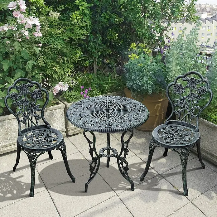 SONNENH Balkonmöbel-Set - 3 -tlg., Eisen, Grün - Antikgrünes Gusseisen-Bistrotisch-Set mit Rosenmotiven, runder Tisch und zwei Stühle, auf einer Terrasse mit Pflanzen.