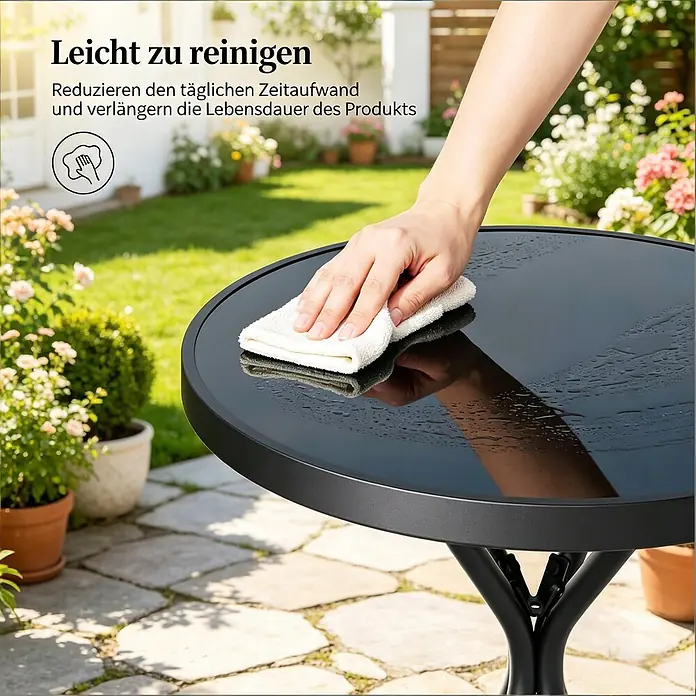 SONNENH Balkonmöbel-Set - 3 -tlg., Glas, Eisen, Polypropylen, Klappbar, Schwarz - Eine Hand wischt Wasser von einem schwarzen, runden Gartentisch mit einem weißen Tuch ab, was seine leicht zu reinigende Oberfläche zeigt.