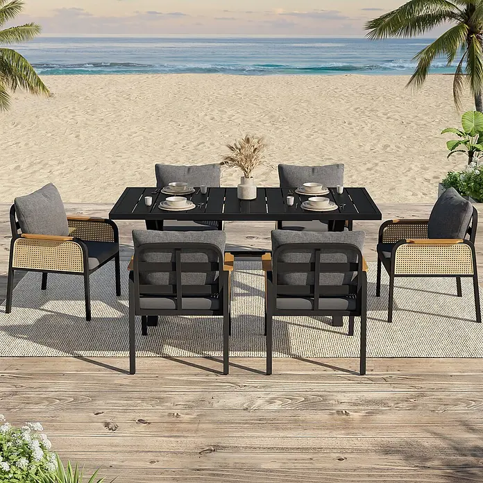 SONNENH Gartenmöbel-Set - 6 -tlg., Eisen, Polyester, Schwarz/Natur - Eine Outdoor-Essgruppe mit schwarzem Tisch und Stühlen mit grauen Kissen und natürlichem Rattan, auf einer Holzterasse am Sandstrand.