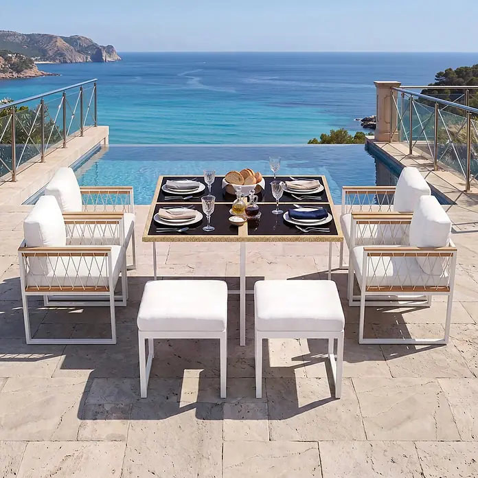 SONNENH Gartenmöbel-Set - 7 -tlg., Schaumstoff, Metall, Rattan, Textil, Natur/Weiß - Outdoor-Essgruppe mit weißen Stühlen, Hockern und einem Tisch mit dunkler Platte am Infinity-Pool mit Meerblick.
