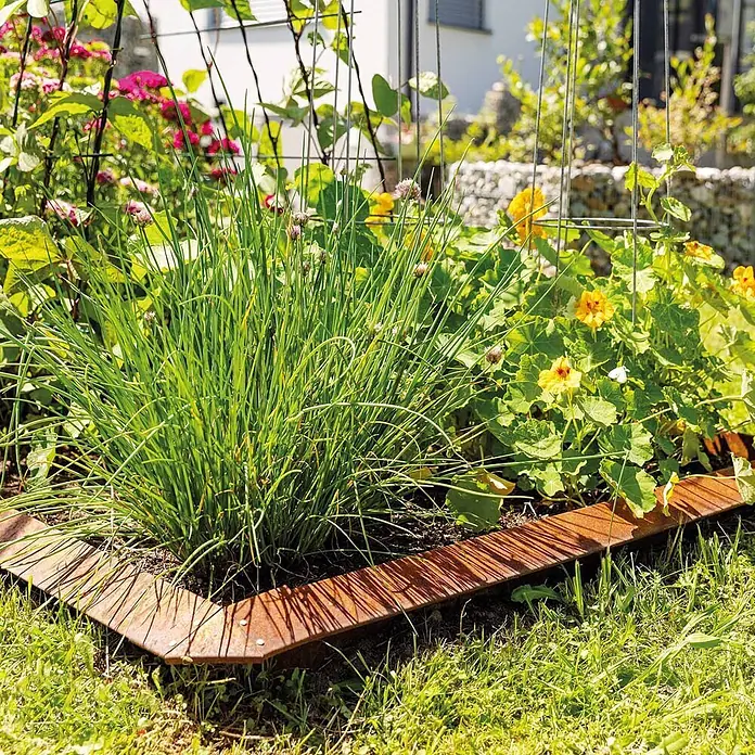 Bellissa Schneckenblech Corten - Cortenstahl, Rost, 100 x 20 cm - Rostige Cortenstahl-Beeteinfassung rahmt eine Gartenecke zwischen Pflanzen ein.