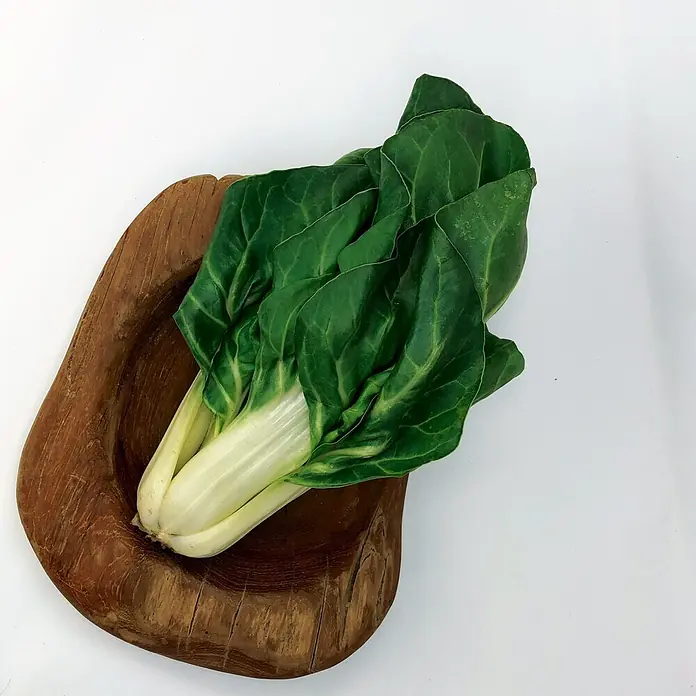 Deine Gartenwelt Mangold Lucullus -  - Frisches grünes Pak Choi mit weißen Stielen in einer rustikalen Holzschale.