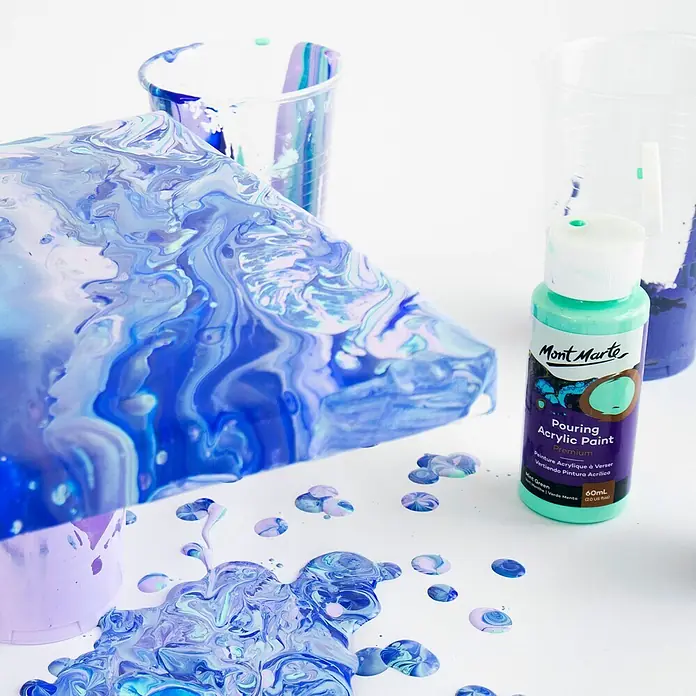 Mont Marte Acrylfarben-Set Premium Ethereal - mehrfarbig, 4 Stk. x 60 ml, Flasche - Mintgrüne Flasche Mont Marte Pouring Acrylfarbe neben marmorierter blauer und violetter Pouring-Kunst.