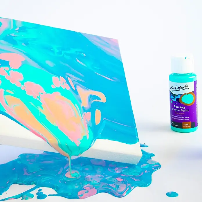 Mont Marte Acrylfarben-Set Premium Flamingo - mehrfarbig, 4 Stk. x 60 ml, Flasche - Flasche Mont Marte Pouring Acrylfarbe neben einer Leinwand, auf der lebendige türkis-, pink- und orangefarbene Fluid Art entsteht.