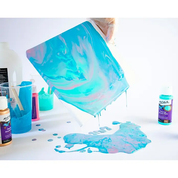 Mont Marte Acrylfarben-Set Premium Flamingo - mehrfarbig, 4 Stk. x 60 ml, Flasche - Hand gießt türkise und pinke Mont Marte Acrylfarbe auf Leinwand für Fluid Art, Farbflaschen daneben.