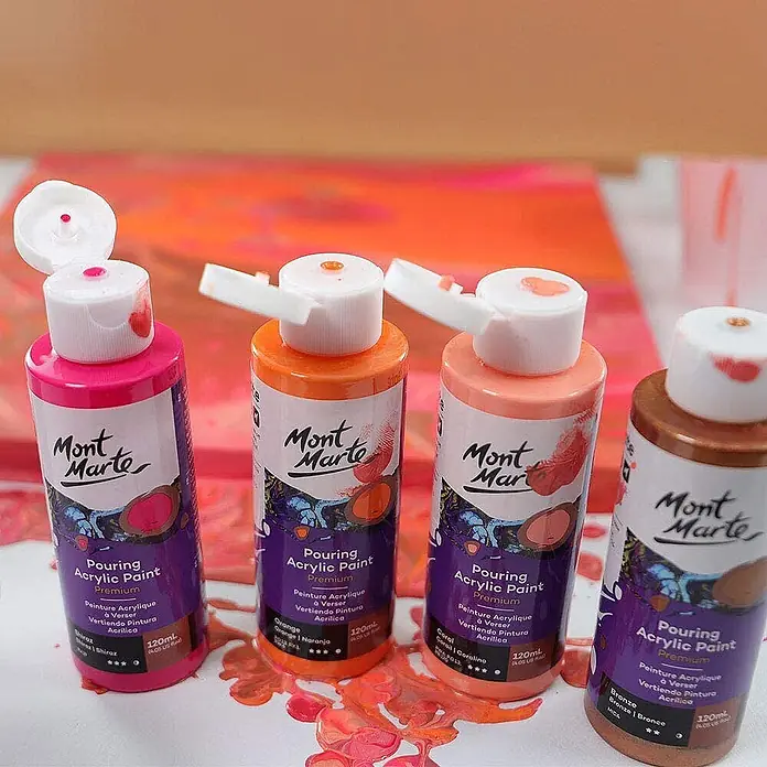 Mont Marte Acrylfarben-Set Premium Coral - mehrfarbig, 4 Stk. x 120 ml, Flasche - Vier Flaschen Mont Marte Pouring Acrylfarbe in Pink, Orange, Koralle und Bronze, mit etwas Farbe auf der Oberfläche.