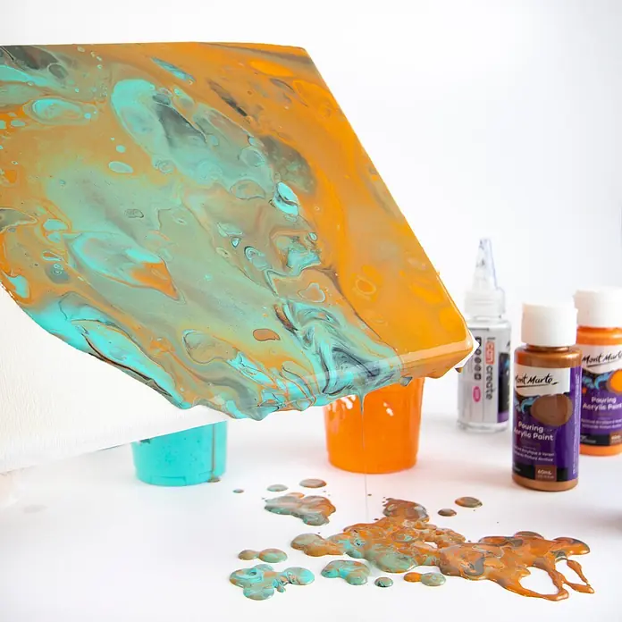 Mont Marte Acrylfarben-Set Premium Galaxy - mehrfarbig, 4 Stk. x 60 ml, Flasche - Flüssige Acrylfarben in Türkis, Orange und Bronze werden auf eine Leinwand gegossen und tropfen herunter, um ein abstraktes Design zu schaffen.