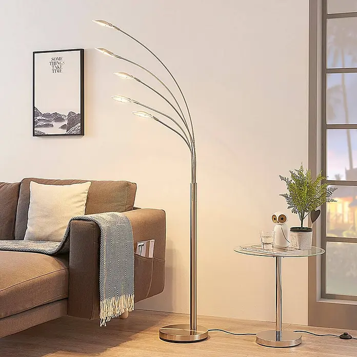Lindby LED Stehlampe Wohnzimmer in nickel matt, weiß, Stehleuchte -  - Moderne LED-Stehleuchte in Silberoptik mit fünf gewölbten Armen, die ein Wohnzimmer neben einem braunen Sofa beleuchtet.
