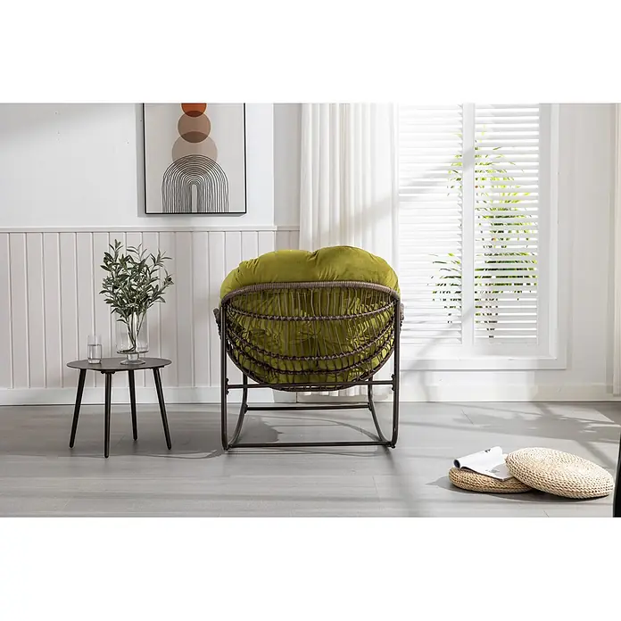 SONNENH Garten-Loungesessel - 20 Stk., Stahl, Rückenlehne verstellbar, Olivgrün, B x T x H: 78 x 106 x 90 cm - Rattan-Schaukelstuhl mit plüschigem grünem Kissen in einem hellen Wohnraum mit Beistelltisch und Pflanze.