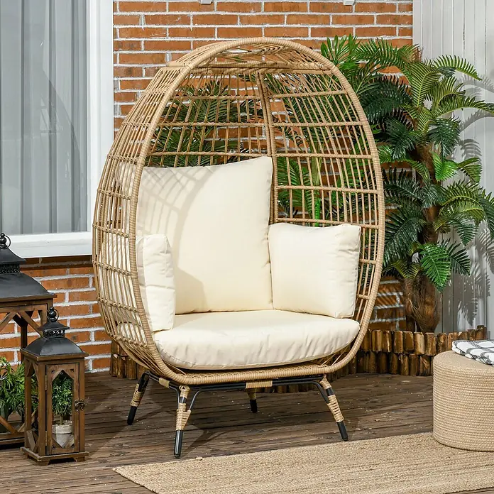 SONNENH Garten-Loungesessel - 1 Stk., Stahl, Khaki, B x T x H: 105 x 97 x 150 cm - Beigefarbener Eiersessel aus Korbgeflecht mit cremefarbenen Kissen auf einer Holzterrasse, vor einer Ziegelwand und Pflanzen.