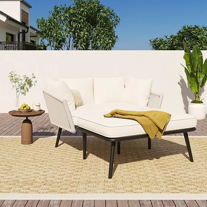 SONNENH Garten-Loungesessel - 1 Stk., Polyester, Beige - Cremefarbenes Outdoor-Loungesofa mit schwarzem Gestell und passendem Ottoman auf einem Webteppich auf Holzdeck.