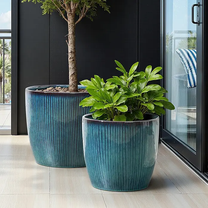 Hometopia Pflanztopf HTPL0081-L - 1 Stk., Außenmaß (Ø x H): 38 x 34,5 cm, Keramik, Blaugrün - Zwei glasierte, gerippte Keramik-Pflanzgefäße in Petrolblau mit Pflanzen auf einem modernen Balkon.