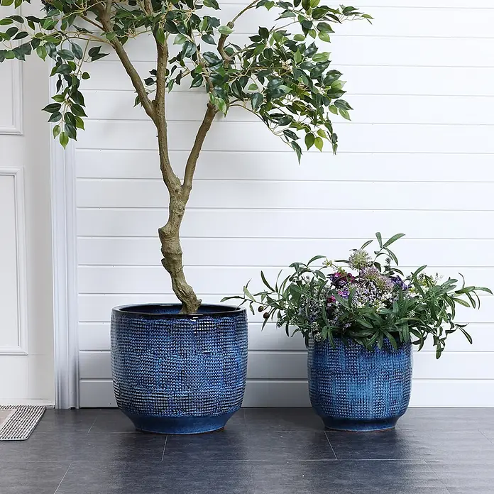 Hometopia Pflanztopf HTPL0036-L - 1 Stk., Außenmaß (Ø x H): 40 x 28,5 cm, Keramik, Marineblau - Zwei blaue, strukturierte Keramikpflanzgefäße unterschiedlicher Größe mit einem Baum und Blumen auf dunklem Boden.