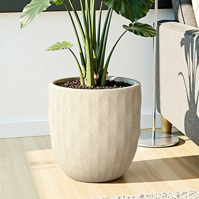 Hometopia Pflanztopf HTPL0183 - Außenmaß (Ø x H): 34 x 34 cm, Verbundwerkstoff, Apricot - Ein großer, strukturierter hellbeiger Pflanztopf mit einer grünen Pflanze auf einem hellen Holzboden.
