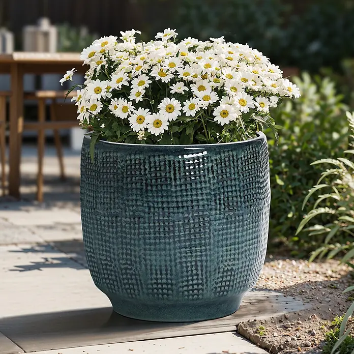 Hometopia Pflanztopf HTPL0037-M - 1 Stk., Außenmaß (Ø x H): 31 x 29 cm, Keramik, Dunkelgrün - Großer türkiser Keramiktopf mit Strukturmuster, gefüllt mit weißen Gänseblümchen auf einer Terrasse.