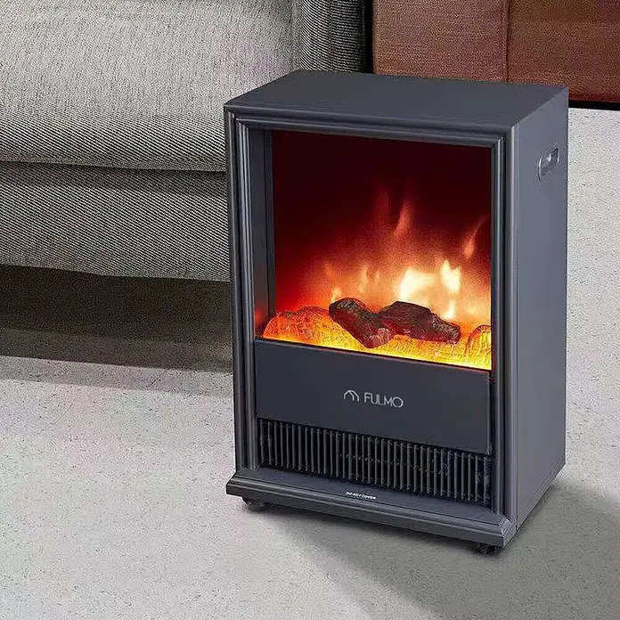 Fulmo Chimenea eléctrica Viena - 2.000 W, 17,5 x 43 x 62,5 cm, Negro - Chimenea eléctrica compacta gris oscuro con efecto de llama realista y troncos brillantes, colocada en el suelo junto a un sofá.