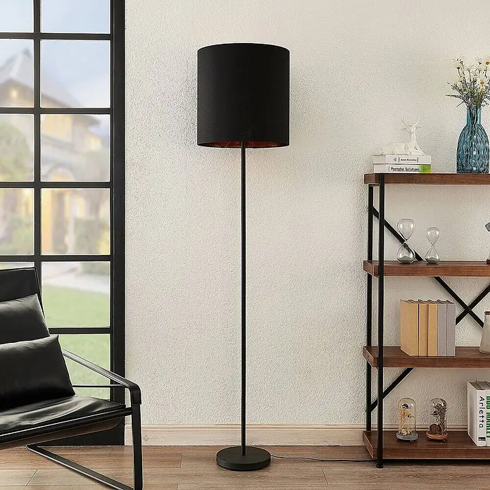 Lindby Stehlampe Wohnzimmer in schwarz, gold, Stehleuchte -  - Eine schwarze Stehleuchte mit zylindrischem Schirm und kupferfarbener Innenseite in einem modernen Wohnzimmer.