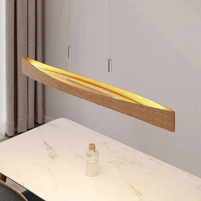 Lindby Pendelleuchte Beazina - Holz hell, nickel matt, holz hell - Hölzerne lineare Pendelleuchte mit warmem Lichtschein über einem weißen Marmortisch.
