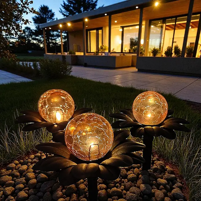 DAPO Solar-Dekoleuchte Flora mit Kugel in Bernsteinoptik - L x B x H: 15 x 15 x 20 cm, Rostfarbig - Drei bernsteinfarbene Solar-Gartenleuchten aus Craqueléglas auf dunklen Blütenstielen beleuchten Gartenweg in der Dämmerung.