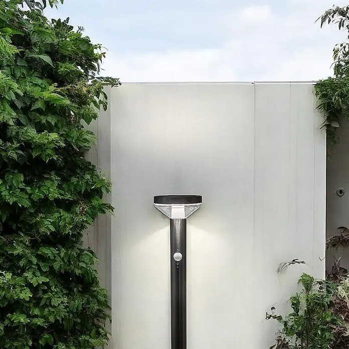 DAPO Solar-Sockelleuchte Solar Wegeleuchte Brok 50cm Silber - L x B x H: 12,5 x 12,5 x 80 cm, silber, IP44 - Dunkle Solar-Gartenleuchte mit Bewegungssensor, beleuchtet eine weiße Wand im Freien.
