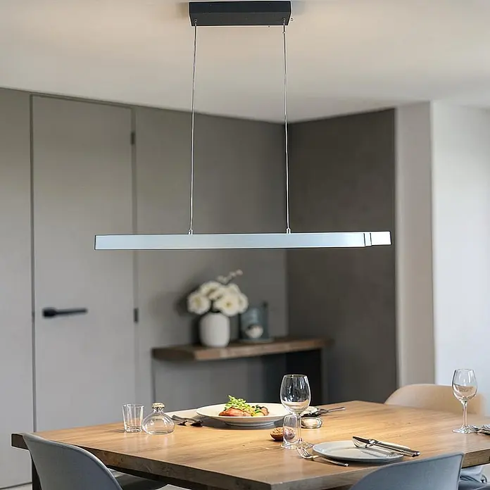 DAPO LED-Pendelleuchte Pendelleuchte "Oslo" ausziehbar, Dimmbar - L x B x H: 125 x 6,8 x 150 cm, Silber, Neutralweiß - Eine schlanke, silberne lineare Pendelleuchte hängt über einem Holztisch und beleuchtet einen modernen Essbereich.