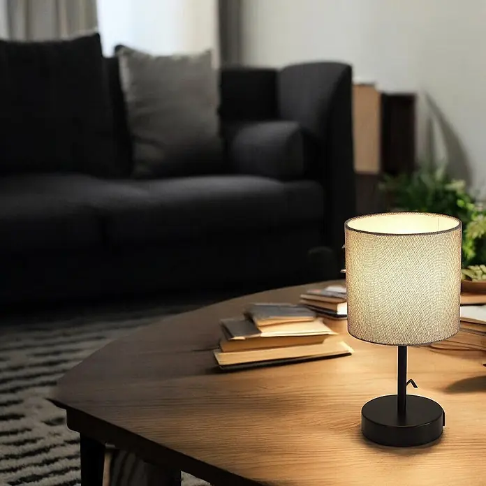 DAPO Tischleuchte Alan Schwarz / Grau mit USB Anschluss - L x B x H: 16 x 16 x 26 cm, Grau, E14 - Schwarze Tischlampe mit hellem Stoffschirm, die ein warmes Licht auf einem Holztisch im Wohnzimmer wirft.