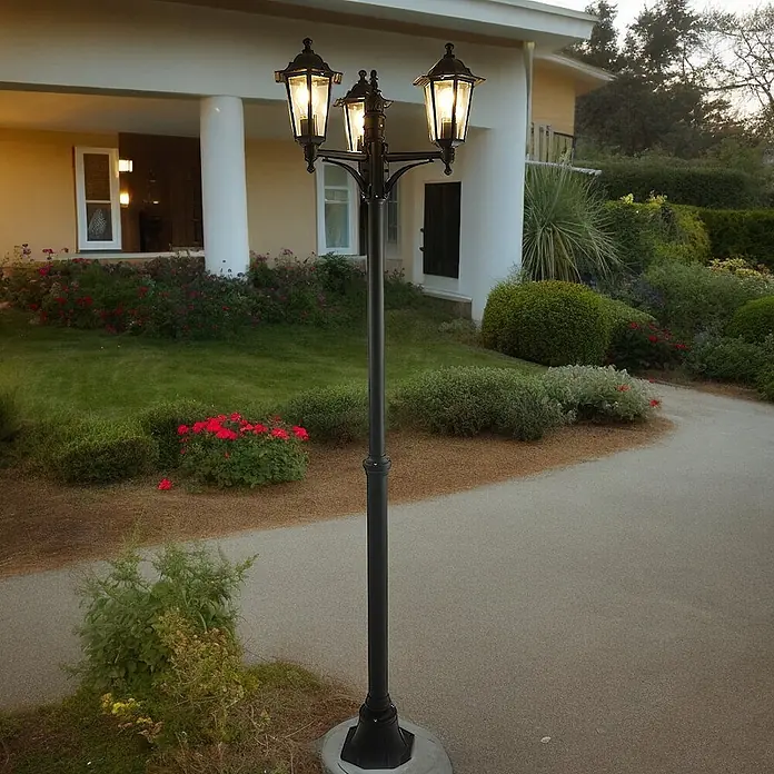DAPO Kandelaber Kingston 3 flg. schwarz - Farbe Gehäuse: Schwarz, 26 x 26 x 200 cm, Ohne Leuchtmittel - Schwarze Metall-Außenlaterne mit drei Lichtern, die einen Gartenweg und ein Haus in der Dämmerung beleuchtet.