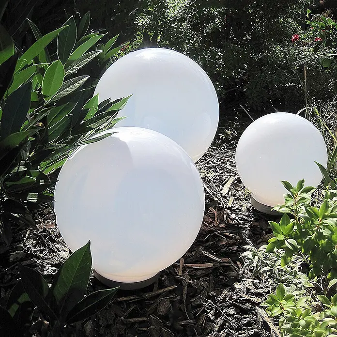 DAPO Solarleuchten-Set Ola 20 - L x B x H: 20 x 20 x 35 cm, Weiß, IP44 - Weiße kugelförmige Gartenleuchten zwischen Grünpflanzen und Rindenmulch.