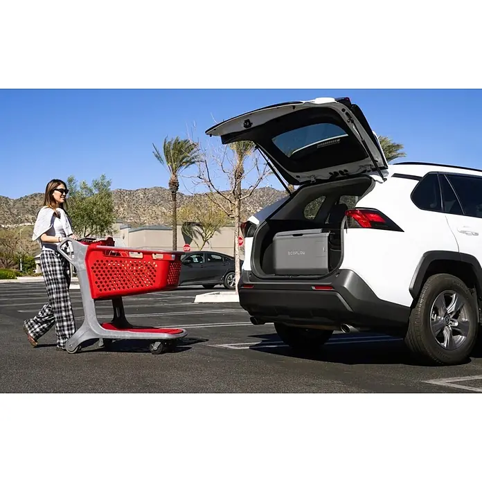 EcoFlow Akku-Kühlbox Glacier - 1 Akku, L x B x H: 48 x 70,6 x 46,6 cm, 55 l - Graue EcoFlow tragbare Powerstation im geöffneten Kofferraum eines weißen SUV, wird auf einem Parkplatz ein-/ausgeladen.