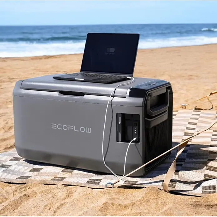 EcoFlow Akku-Kühlbox Glacier - 1 Akku, L x B x H: 40,5 x 70,6 x 40 cm, 35 l - Graue Ecoflow-Powerstation am Strand, lädt einen Laptop.