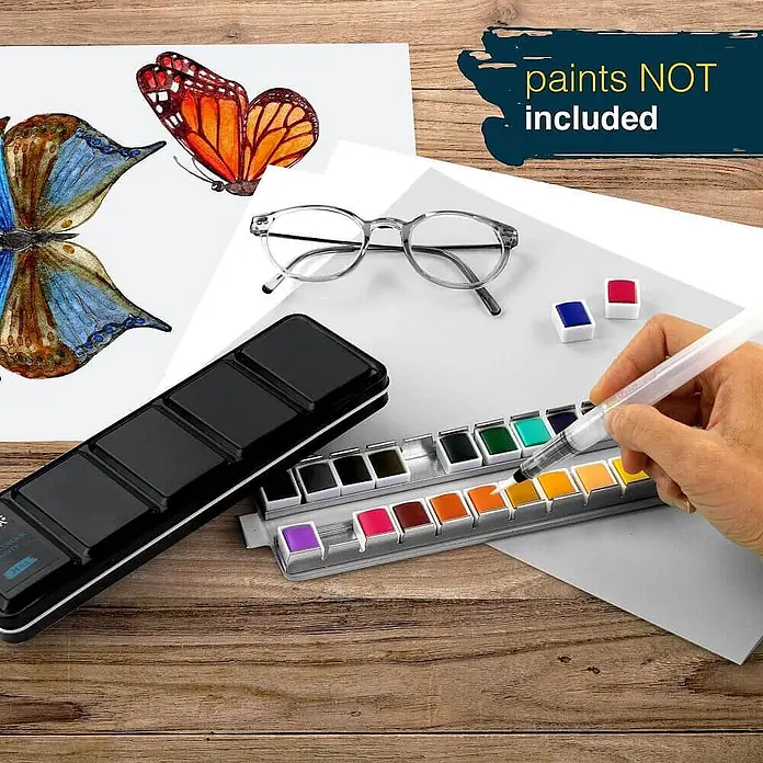 Colaro 24 Fächer Aquarellkasten Leer -  - Eine Hand benutzt einen klaren Wasserpinsel auf einer schwarzen Aquarellpalette, umgeben von bemalter Schmetterlingskunst.
