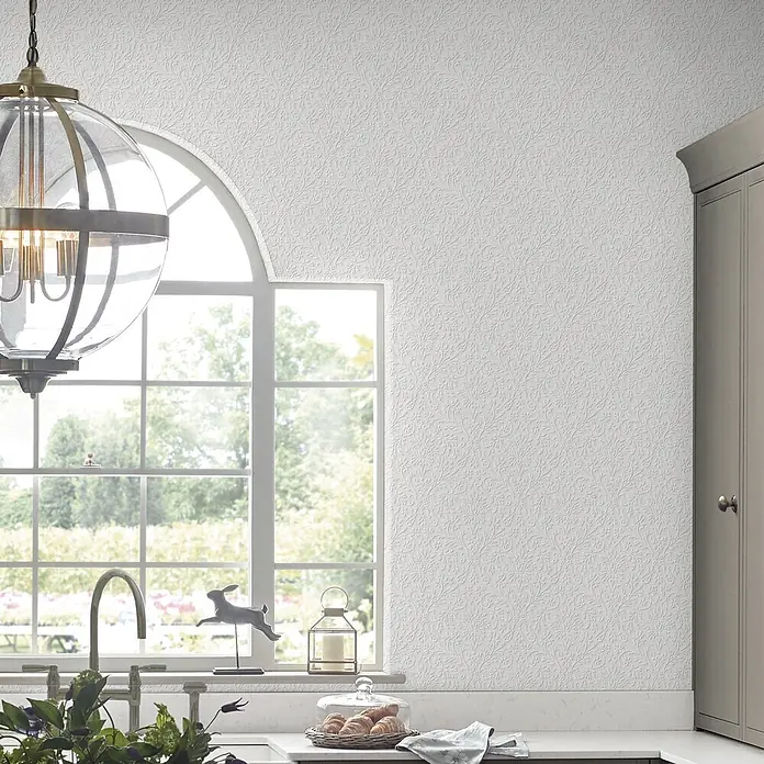 Laura Ashley Vliestapete Annecy - Weiß, Ornament, 10 x 0,52 m - Weiße geprägte Tapete mit aufwendigem Blumenmuster an einer Küchenwand, hinter einem Fenster und Schränken.
