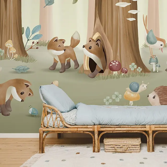 Little Dutch Fototapete Waldfreunde - Vlies - Natürliches Rattan-Kinderbett mit hellblauer Bettwäsche, in einem Zimmer mit Waldtiertapete. Ein geflochtener Korb steht darunter.