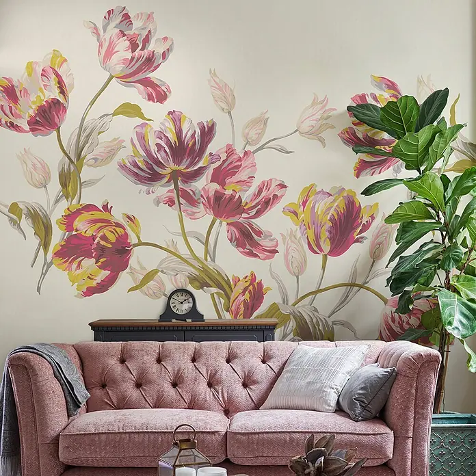 Laura Ashley Fototapete Gosford - Vlies - Ein plüschiges pinkfarbenes Chesterfield-Sofa steht im Wohnzimmer, mit Kissen und einer Decke, zeigt sein elegantes Design und komfortables Aussehen.