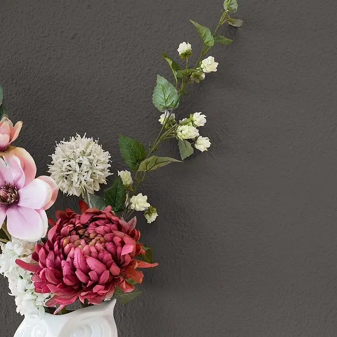 Bricoflor Wandfarbe 2,5 Liter, Rock - grau anthrazit, Matt, 2,5 l, Wasserverdünnbar - Ein Arrangement aus Kunstblumen mit rosa Magnolien, weißen Allium und einer tiefrosa Chrysantheme in einer weißen Vase.