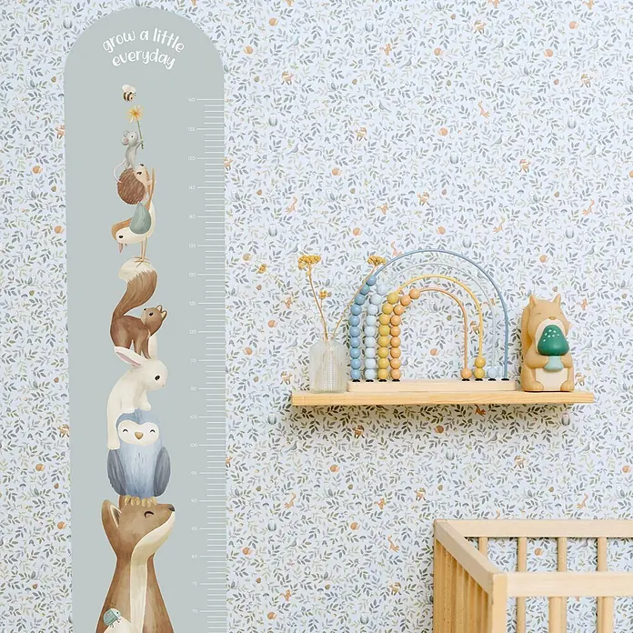 Little Dutch Vliestapete Waldabenteuer - Blau/Grün, Tieroptik, 10 x 0,52 m - Kinderzimmer mit hellblauem Wachstumsdiagramm mit gestapelten Waldtieren und dem Text 'grow a little everyday', neben einem Holzbett.