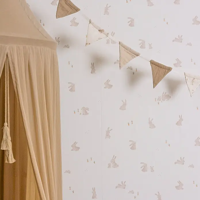 Little Dutch Vliestapete Babykaninchen - Braun/Weiß, Tieroptik, 10 x 0,52 m - Ein hellbeiger Stoffhimmel und passende dreieckige Wimpelkette, in einem Zimmer mit Hasenmuster-Tapete.