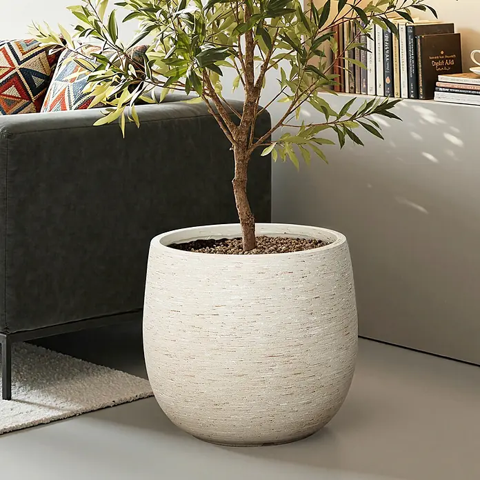 Hometopia Pflanztopf HTPL0166 - Außenmaß (Ø x H): 31 x 31,8 cm, Verbundwerkstoff, Weiß - Großer, hellbeiger strukturierter Pflanzkübel mit grüner Pflanze, neben einem dunkelgrauen Sofa im Wohnzimmer.