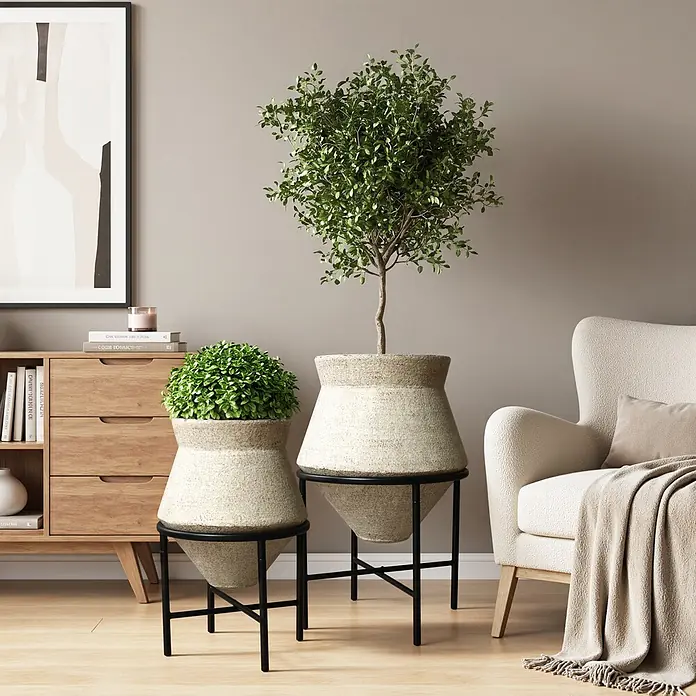 2er Blumentopf Set Frostsicher Formstabil -  - Zwei texturierte Pflanzgefäße auf schwarzen Metallständern mit Pflanzen in einem modernen Wohnzimmer.