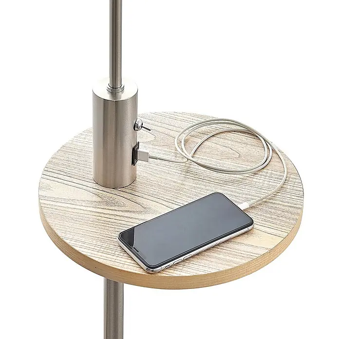 Lindby Stehlampe Wohnzimmer in nickel satiniert, beige, Stehleuchte -  - Runder Holztisch mit integrierter Ladestation aus gebürstetem Metall, auf dem ein Smartphone geladen wird.