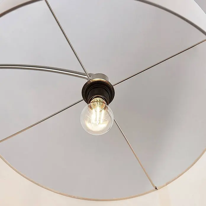 Lindby Stehlampe in nickel satiniert, weiß, Bogenlampe Wohnzimmer -  - Eine leuchtende Klarglas-Glühbirne in einer dunklen Fassung, umgeben von Metallstreben und einem hellen Lampenschirm.