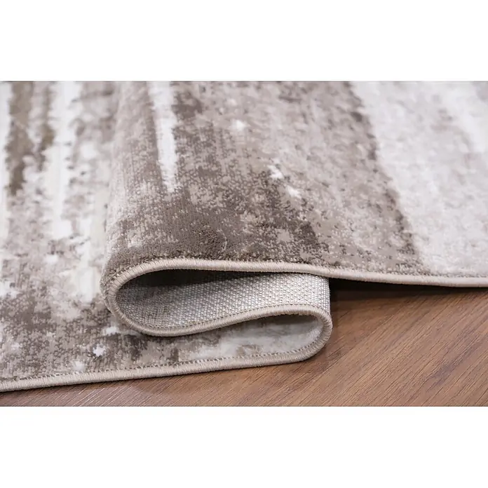 Alfombra de pelo corto Ana - Natural, 110 x 60 cm, 100% poliéster - Alfombra beige-marrón con patrón abstracto parcialmente enrollada sobre suelo de madera, muestra textura y reverso tejido.