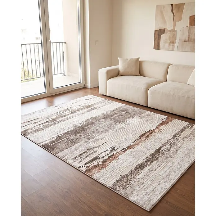 Alfombra de pelo corto Ana - Natural, 110 x 60 cm, 100% poliéster - Una alfombra abstracta beige y marrón desgastada con detalles blancos, sobre un suelo de madera en una sala de estar.