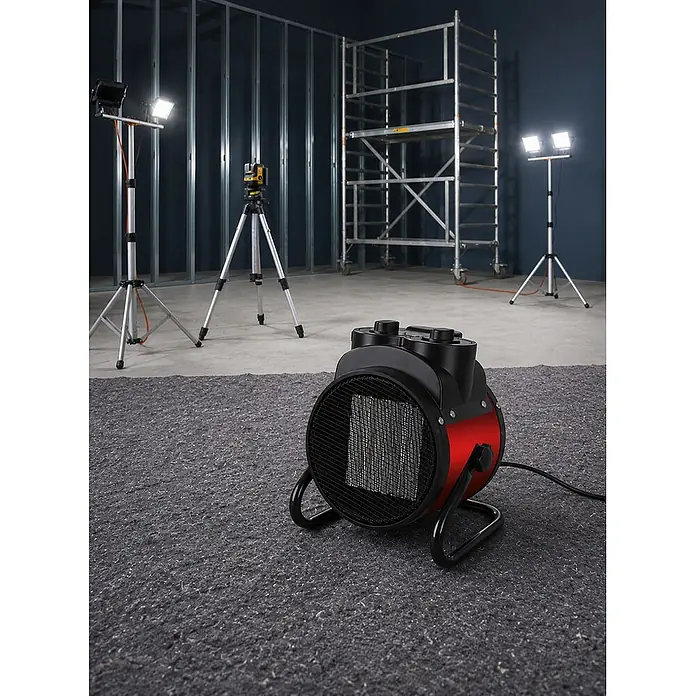 Calefactor industrial Atix - 1.000 kW - 2.000 kW, Rojo/Negro - Calefactor eléctrico rojo y negro sobre una cubierta protectora gris en un entorno de obra.