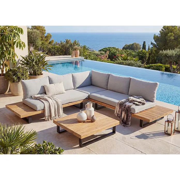 Mendler Loungemöbel-Set HWC-H54 - 2 -tlg., Holz, Hellbraun, Polster hellgrau, Hellbraun, Polster hellgrau - L-förmiges Outdoor-Sofa mit hellgrauen Kissen und Holzrahmen, daneben ein passender Couchtisch auf einer Terrasse.