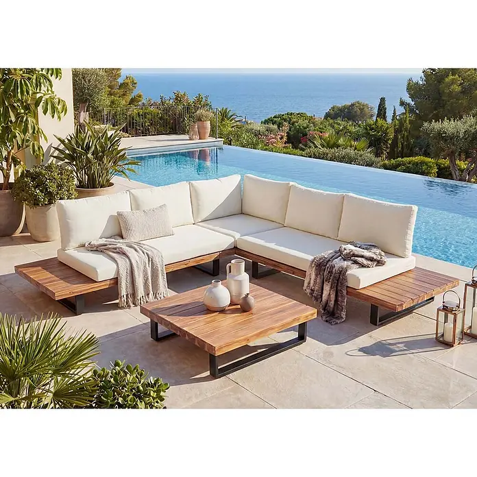 Mendler Loungemöbel-Set HWC-H54 - 3 -tlg., Holz, Hellbraun, Polster cremeweiß, Hellbraun, Polster cremeweiß - Outdoor-Ecksofa aus Holz mit weißen Kissen und Couchtisch auf einer Terrasse am Infinity-Pool, mit Meerblick.
