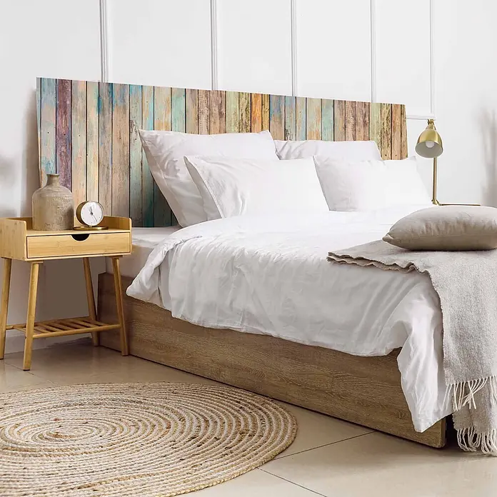 Cabecero de cama Vintage - L x An: 135 x 60 cm, Multicolor - Cabecero de tablas de madera multicolor desgastadas detrás de una cama con ropa blanca, junto a una mesita.
