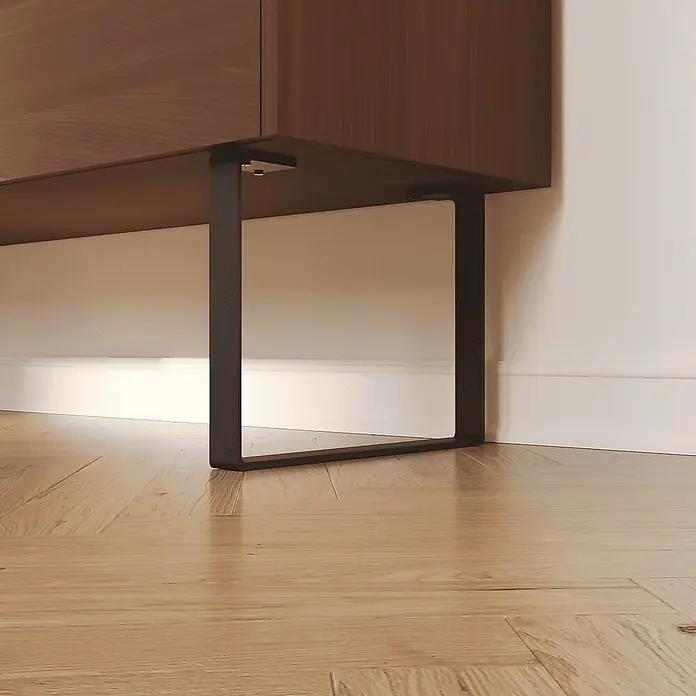 HEVVA Möbelfuß-Set LUXEMBURG - L x B x H: 40 x 4 x 20 cm, Metall, 2 Stk. - Dunkles U-förmiges Metallbein stützt ein Holzmöbelstück, sichtbar auf einem hellen Holzfußboden.
