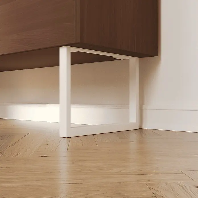 HEVVA Möbelfuß-Set GRAZ - L x B x H: 30 x 3 x 20 cm, Metall, 2 Stk. - Weißes Metallbein, das einen dunkelbraunen Holzschrank trägt, auf hellem Holzboden.